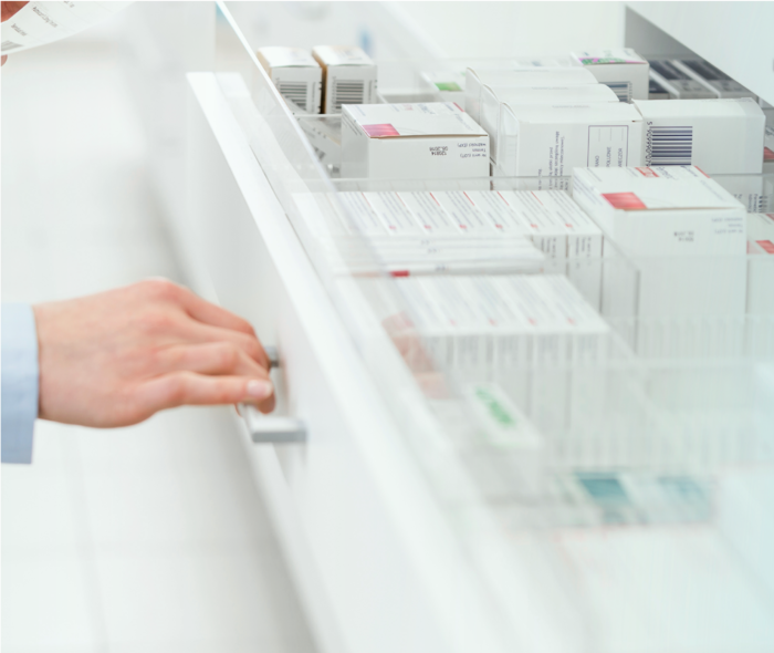 Sichtbar ist eine Hand, die einen Medikamentenschrank öffnet.