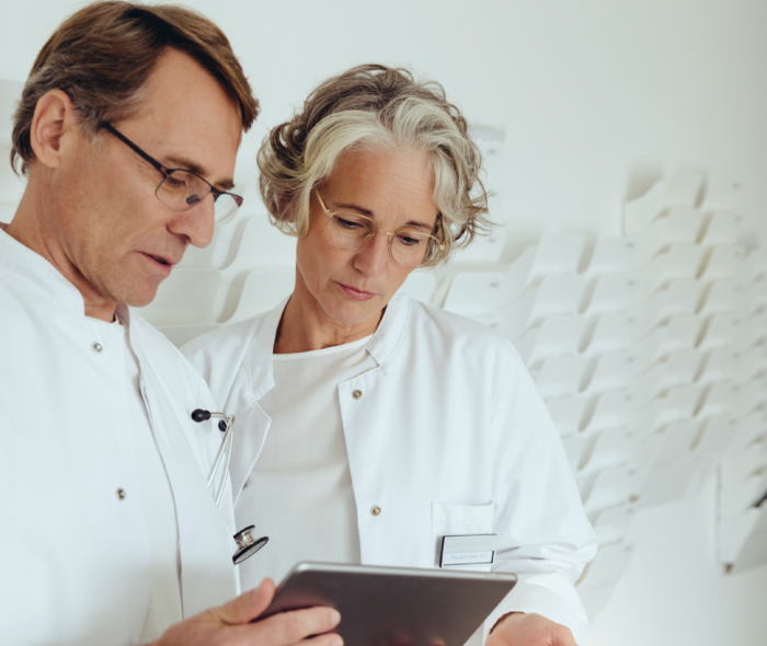 Ein Arzt und eine Ärztin stehen nebeneinander und betrachten einen Befund
