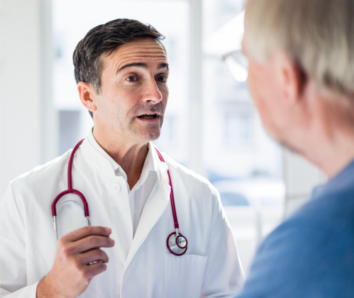 Leben mit Prostatakrebs: Ein Arzt steht einem Patienten gegenüber und spricht. Ein Arzt steht einem Patienten gegenüber und spricht.