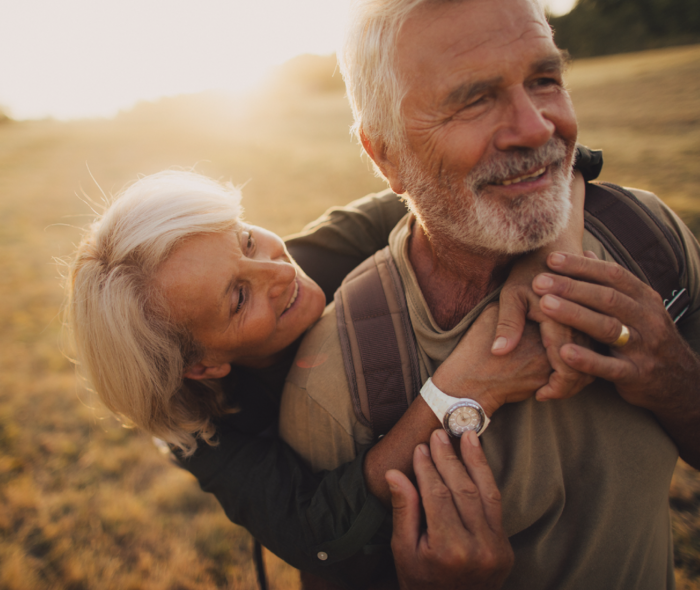Frau umarmt glücklich ihren Mann von hinten.