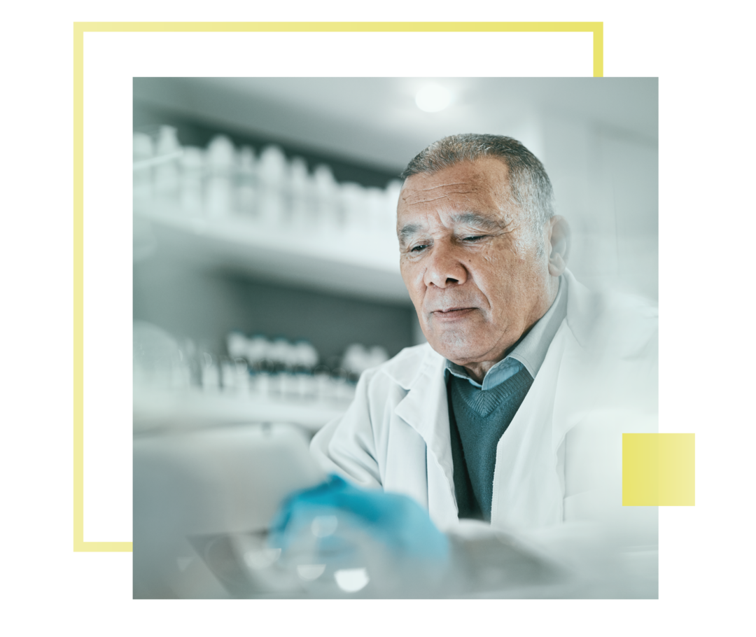 Leben mit Prostatakrebs: Ein Labormitarbeiter mit weißem Kittel sitzt an einem Arbeitsplatz.  Ein Labormitarbeiter mit weißem Kittel sitzt an einem Arbeitsplatz.