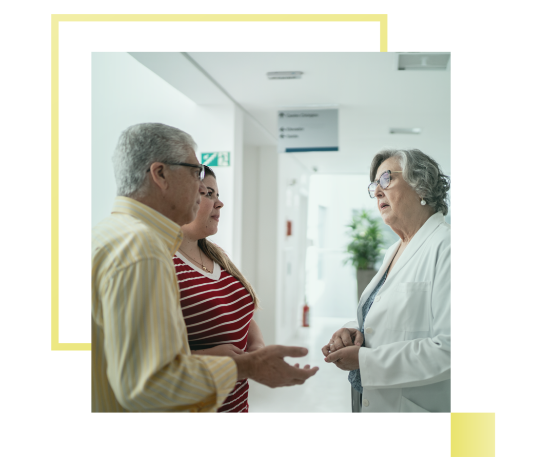 Leben mit Prostatakarzinom: Ein Mann und eine Frau stehen in einem Krankenhaus und sind im Gespräch mit einer Ärztin Ein Mann und eine Frau stehen in einem Krankenhaus und sind im Gespräch mit einer Ärztin.