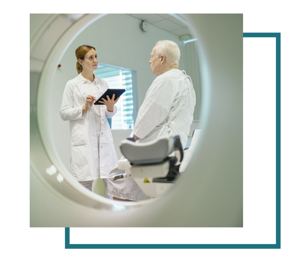 Eine Ärztin hat ein Tablet in der Hand und spricht mit einem Patienten.