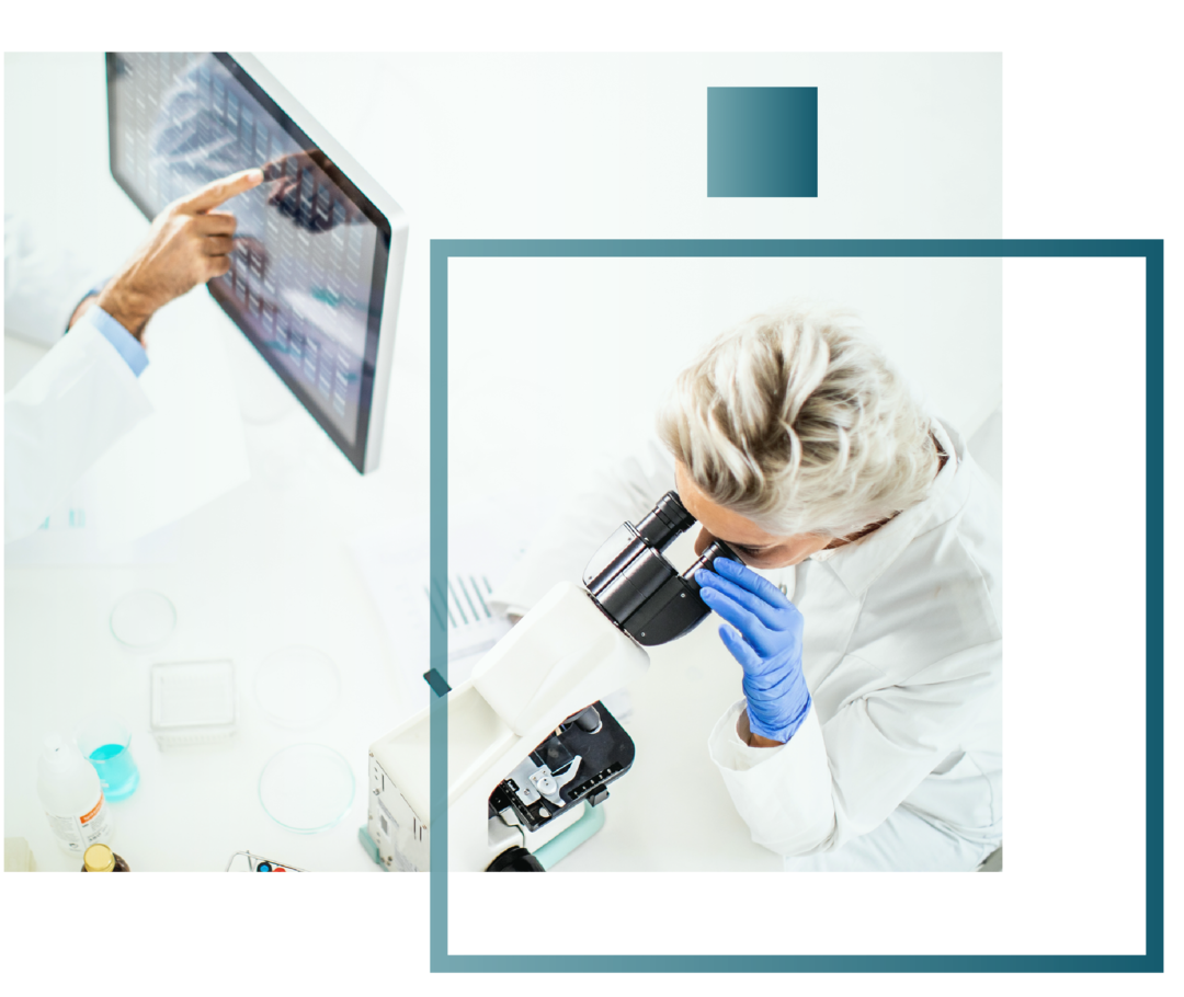 Eine Ärztin sitzt am Tisch und blickt durch ein Mikroskop. 