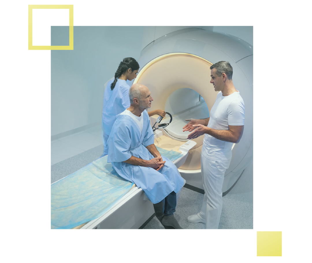 Ein Patient sitzt auf der Liegefläche eines MRT-Gerätes und unterhält sich mit einem Arzt. 