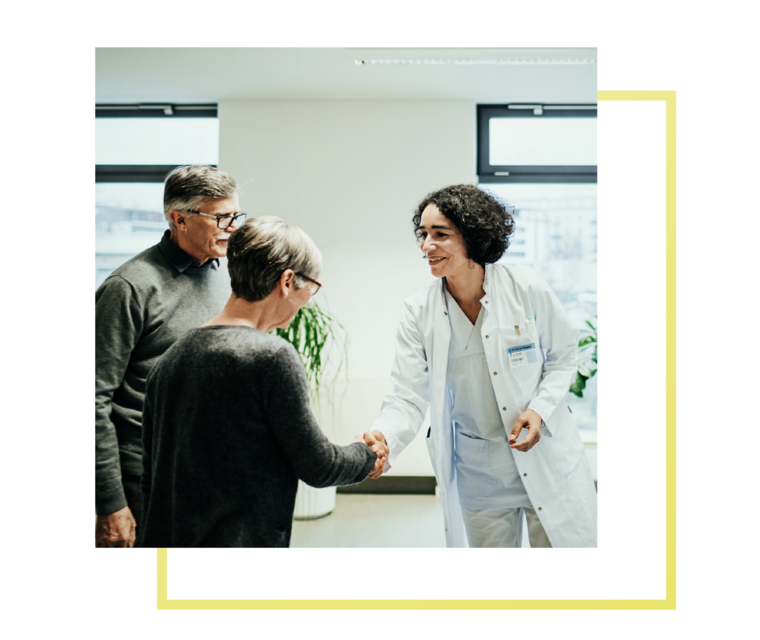 Eine Ärztin ist mit einer Frau und einem Herren im Gespräch und schüttelt der Frau die Hand