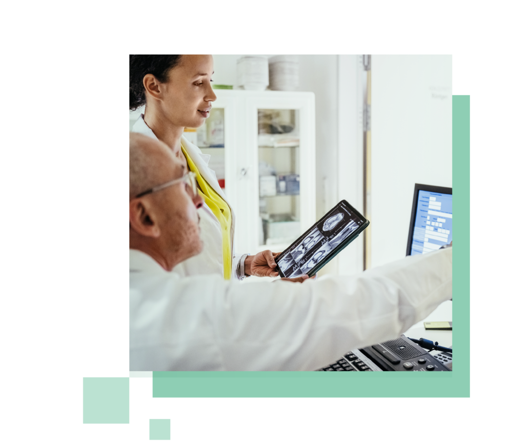 Ein Arzt und eine Ärztin sitzen vor einem Computer und betrachten die Ergebnisse einer Untersuchung.