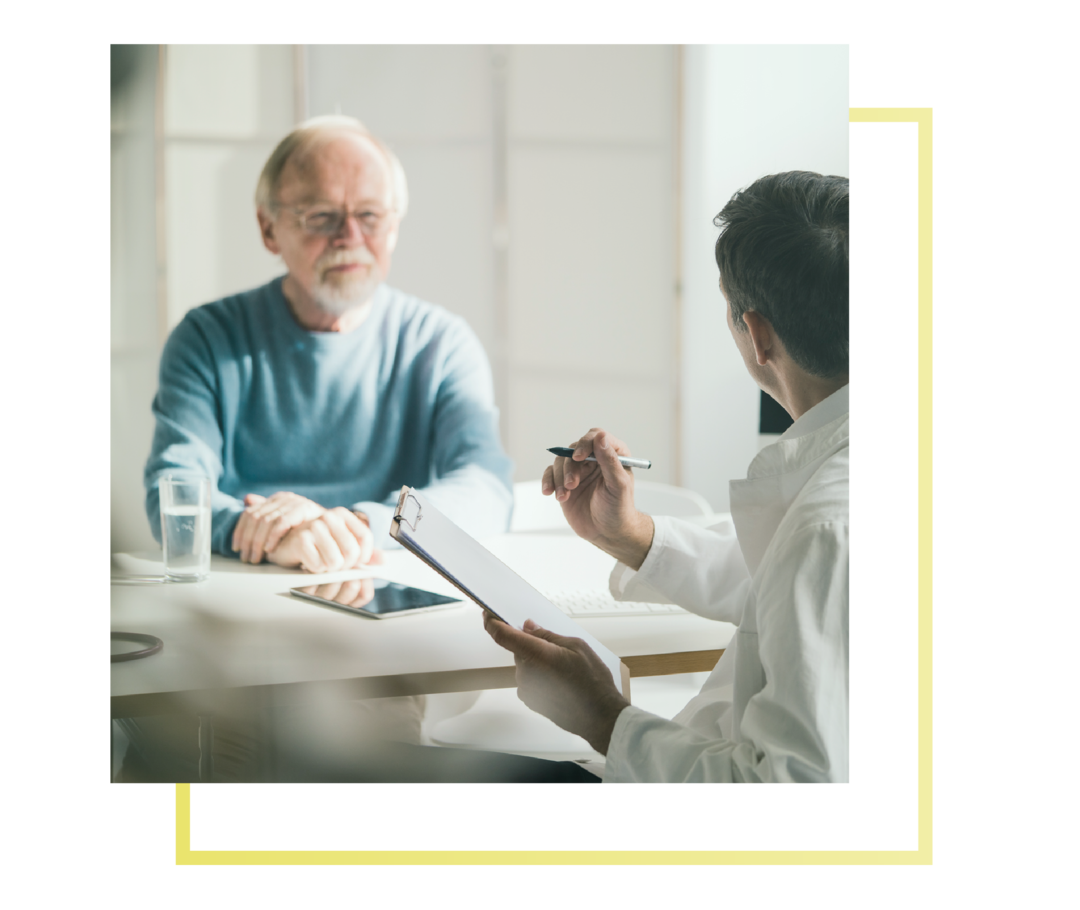 Ein Patient sitzt einem Arzt gegenüber und die beiden sind im Gespräch.