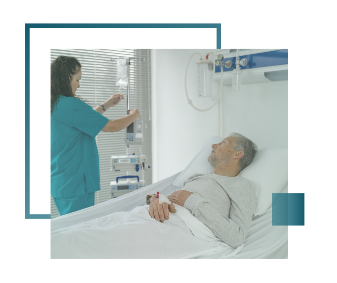 Leben mit Prostatakrebs: Ein Patient liegt in einem Bett und die Schwester bereitet eine Infusion vor.  Ein Patient liegt in einem Bett und die Schwester bereitet eine Infusion vor.