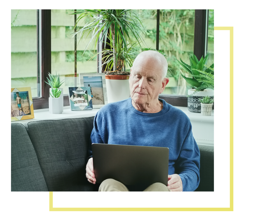 Leben mit Prostatakarzinom: Ein Mann sitzt auf dem Sofa. Er hält auf den Beinen ein Laptop. Ein Mann sitzt auf dem Sofa. Er hält auf den Beinen ein Laptop.