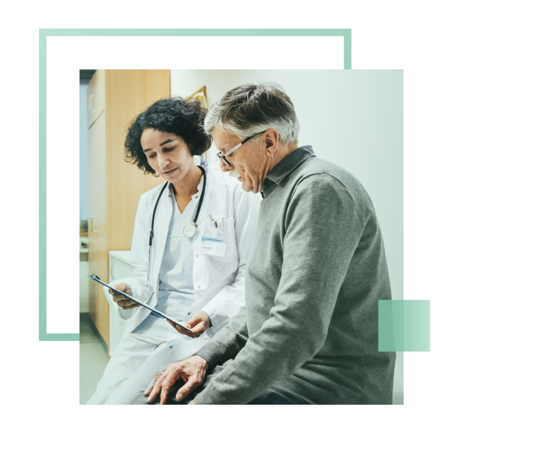 Eine Ärztin und ein Patient sitzen nebeneinander und betrachten einen Befund.