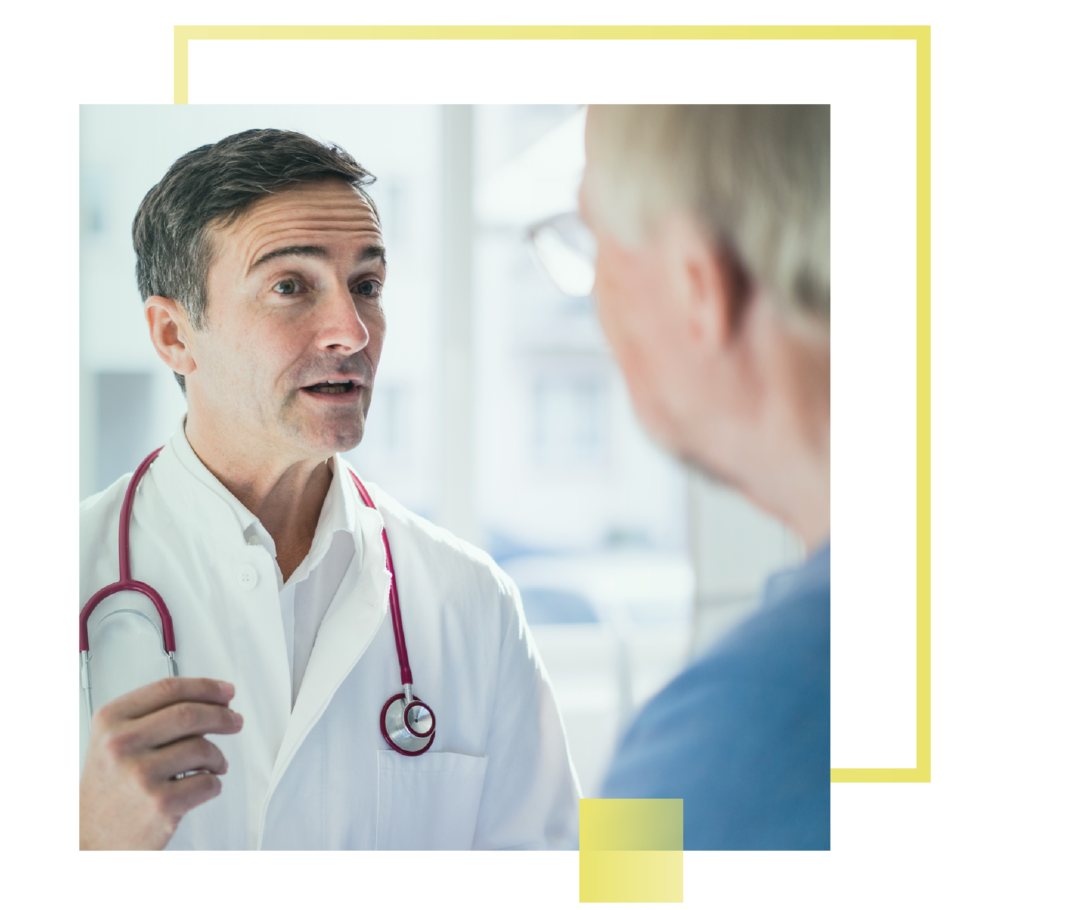 Ein Arzt steht einem Patienten gegenüber und spricht.