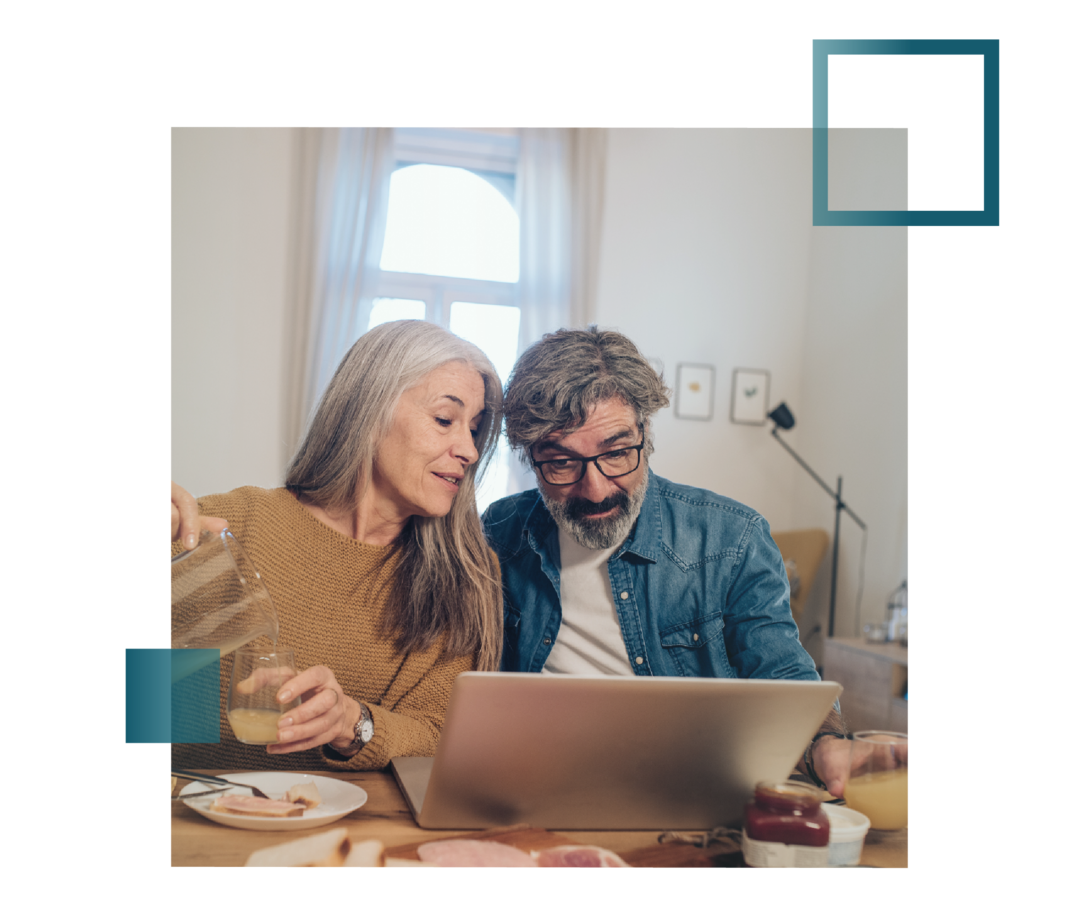 Ehepaar schaut beim Abendessen gemeinsam in den Laptop.