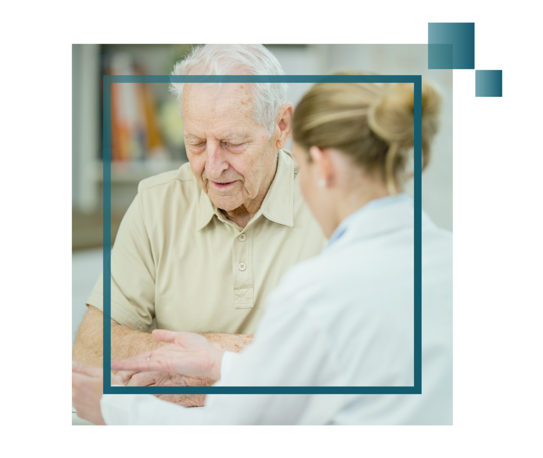 Nach unten schauender älterer Mann im Gespräch mit einer Ärztin.