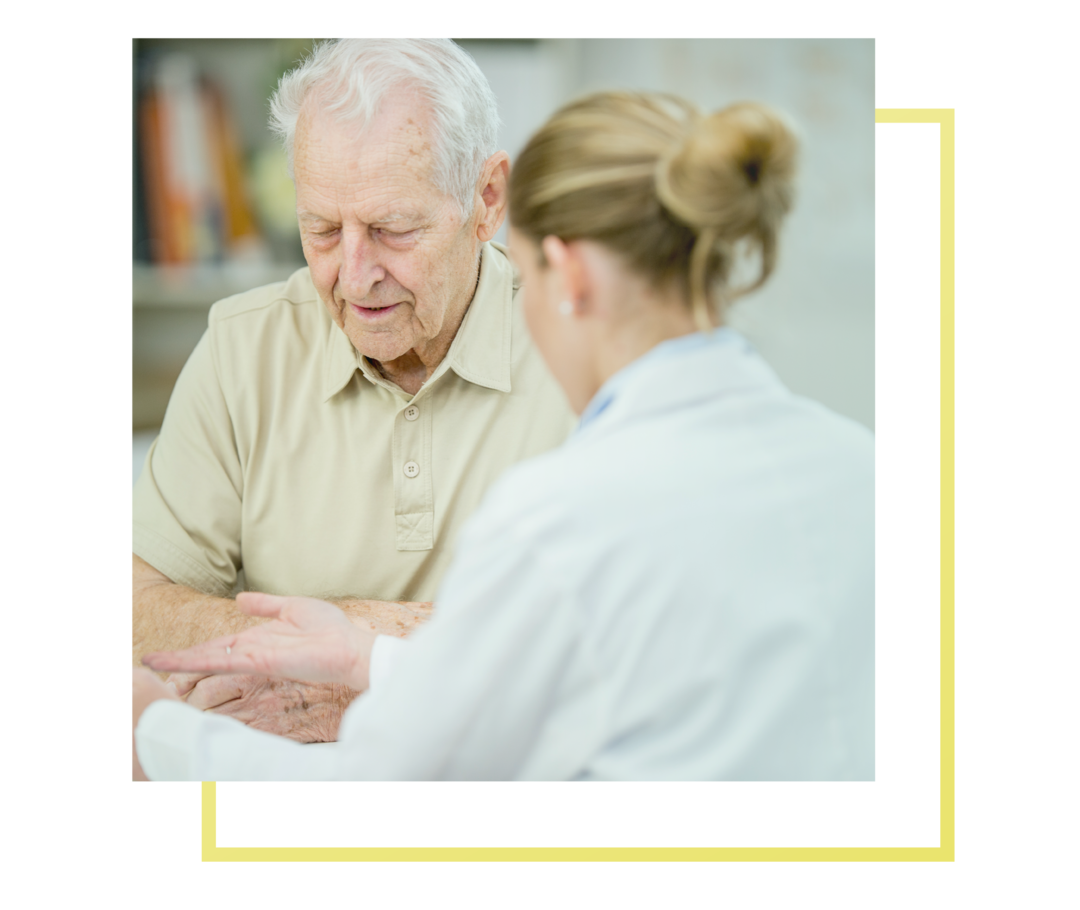 Nach unten schauender älterer Mann im Gespräch mit einer Ärztin.