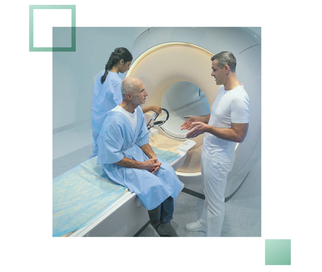 Ein Patient sitzt auf der Liegefläche eines MRT-Gerätes und unterhält sich mit einem Arzt.
